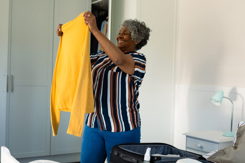 Mulher feliz segurando e olhando para uma blusa amarela recém lavada